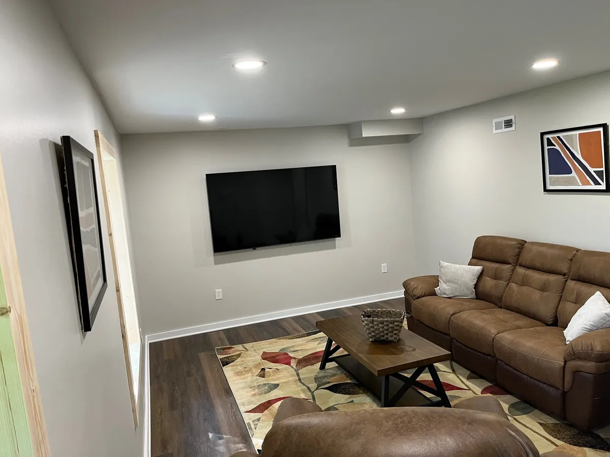 A cozy living room with a plush sofa, coffee table, television, and colorful artwork, inviting guests to relax, watch movies, or share time together indoors.
