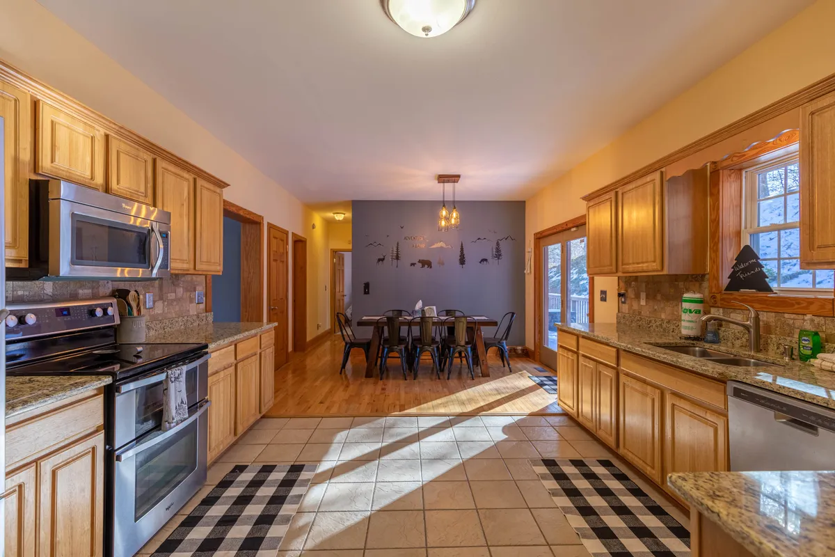 This image captures a well-appointed kitchen featuring granite countertops, stainless steel appliances, and a dining table set for a meal. Decorative wall art adds warmth and personality, while the arrangement invites group cooking and dining experiences.